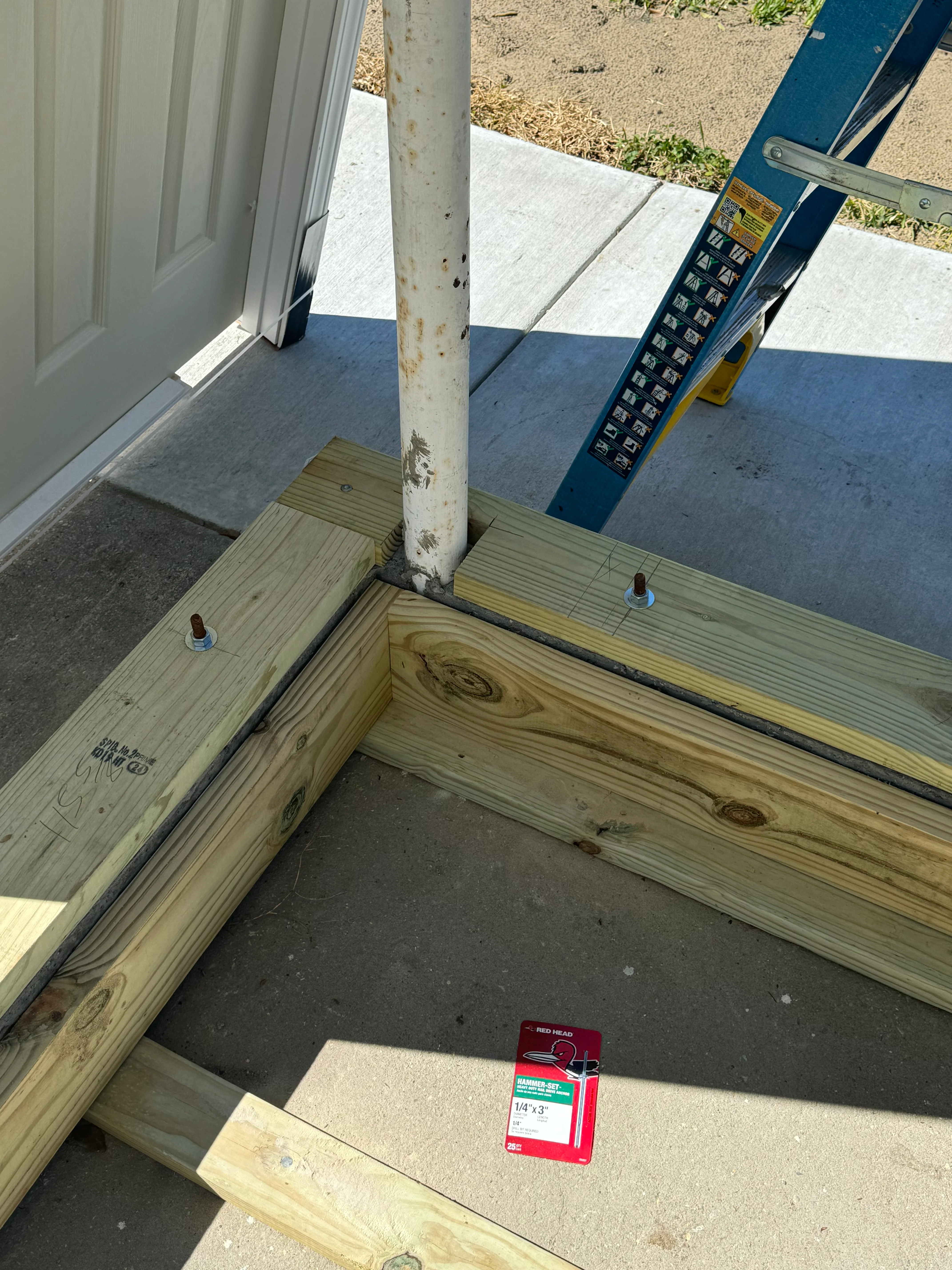 Concrete foundation with pressure-treated lumber framing and structural post installation