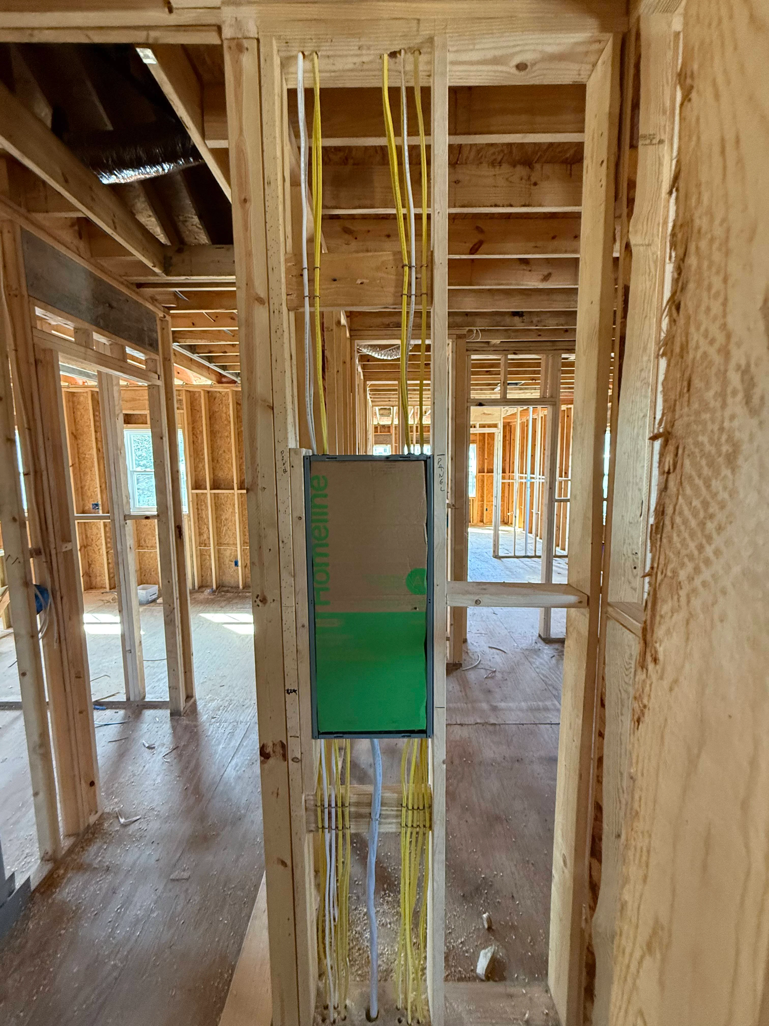 Interior framing with wood studs, yellow electrical conduit, and open floor plan during construction