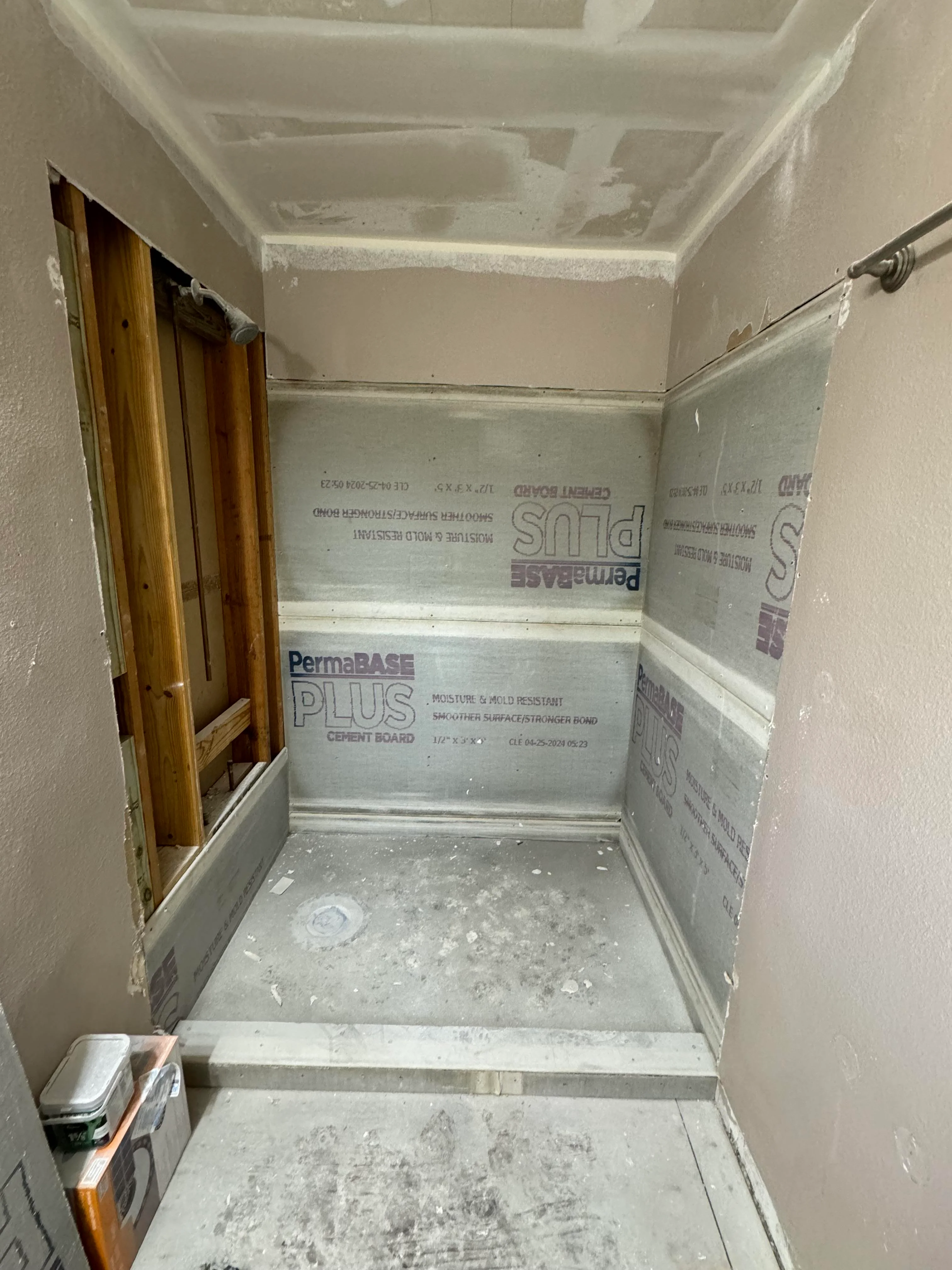 Bathroom under renovation with drywall, cement board, and framing visible