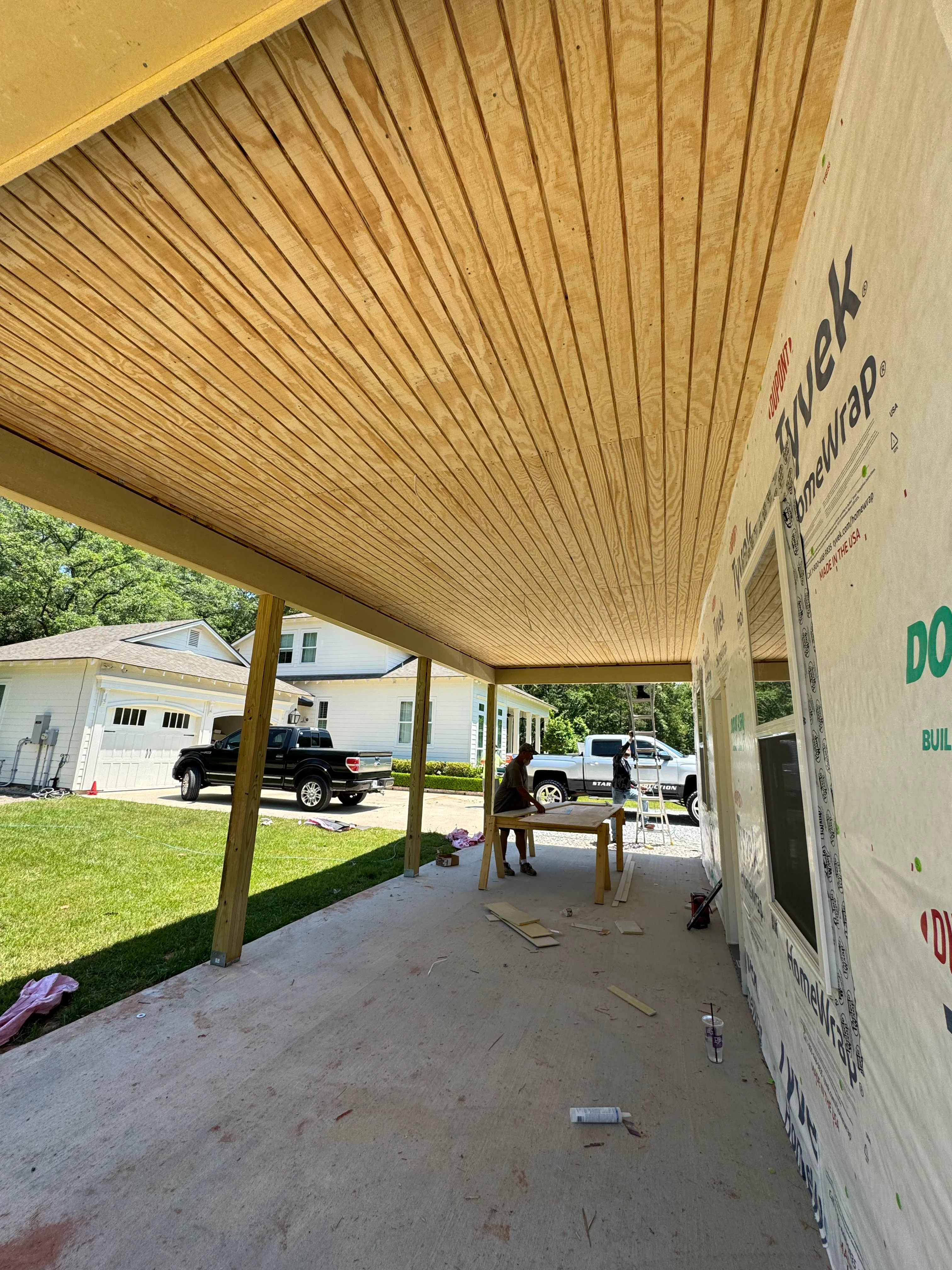 Wood slat patio cover with vertical ceiling detail and support posts over concrete foundation