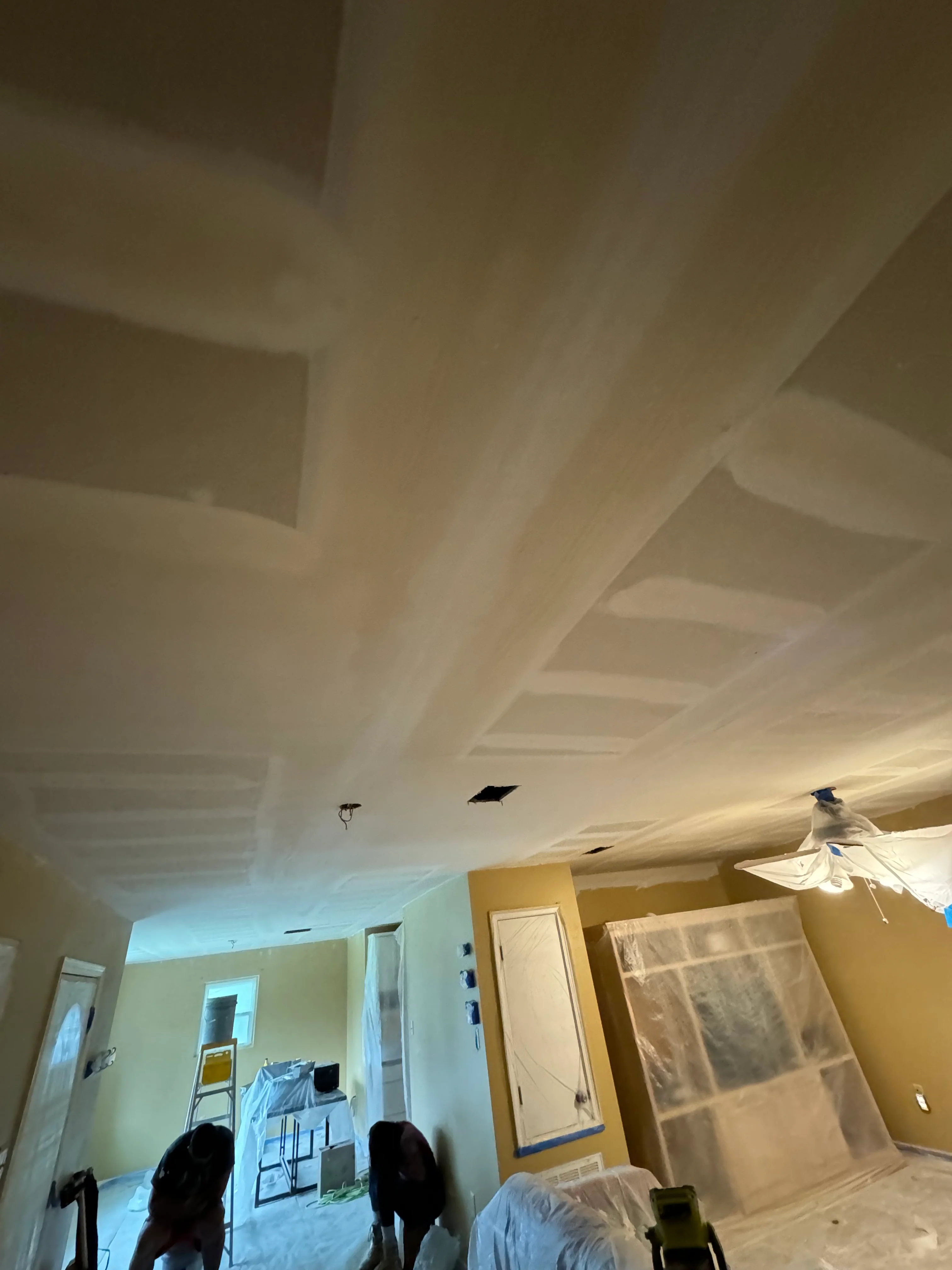 Interior drywall ceiling installation with recessed lighting and finished wall surfaces
