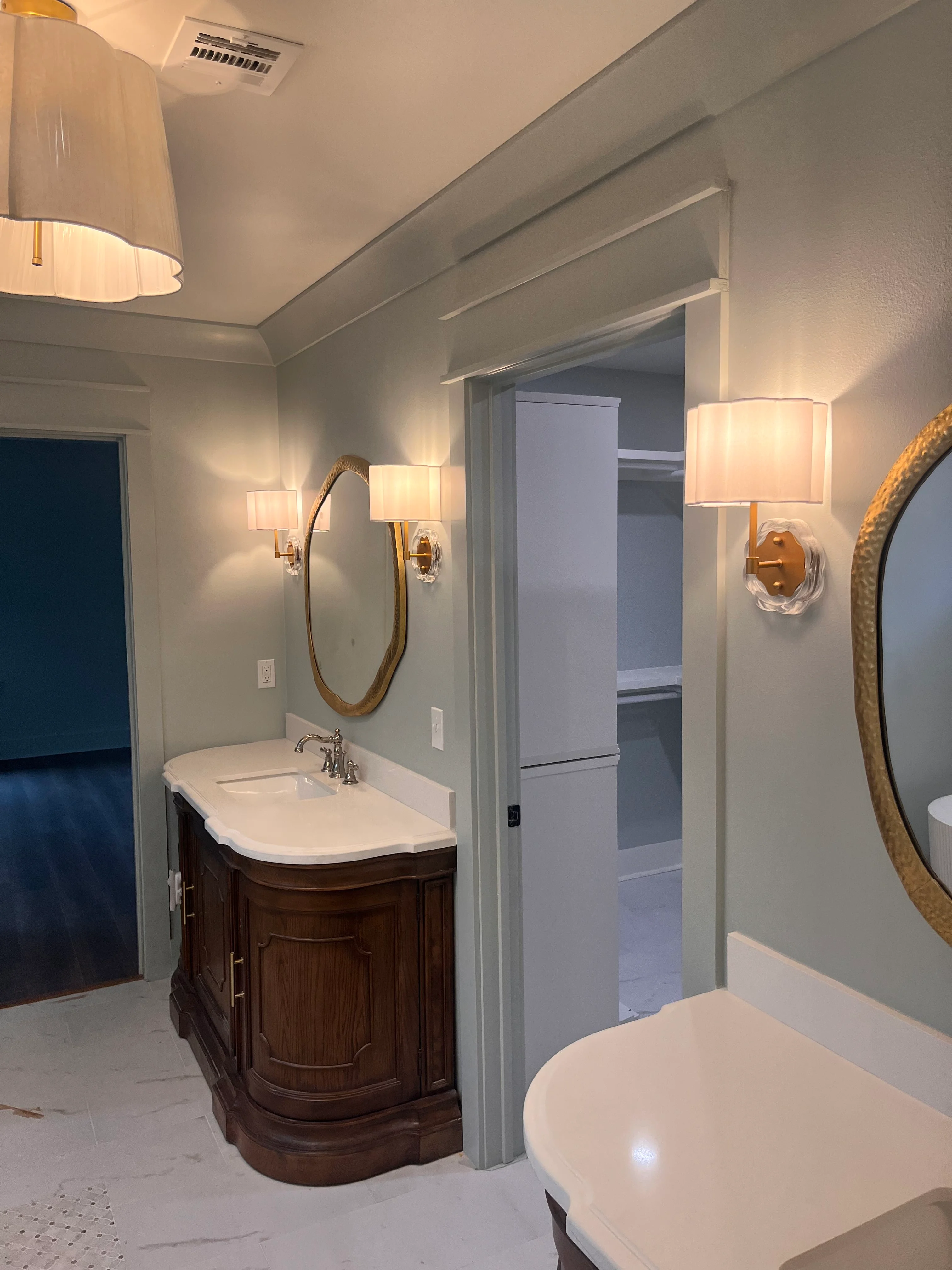 Modern master bathroom with dark wood vanity, dual mirrors, and warm lighting