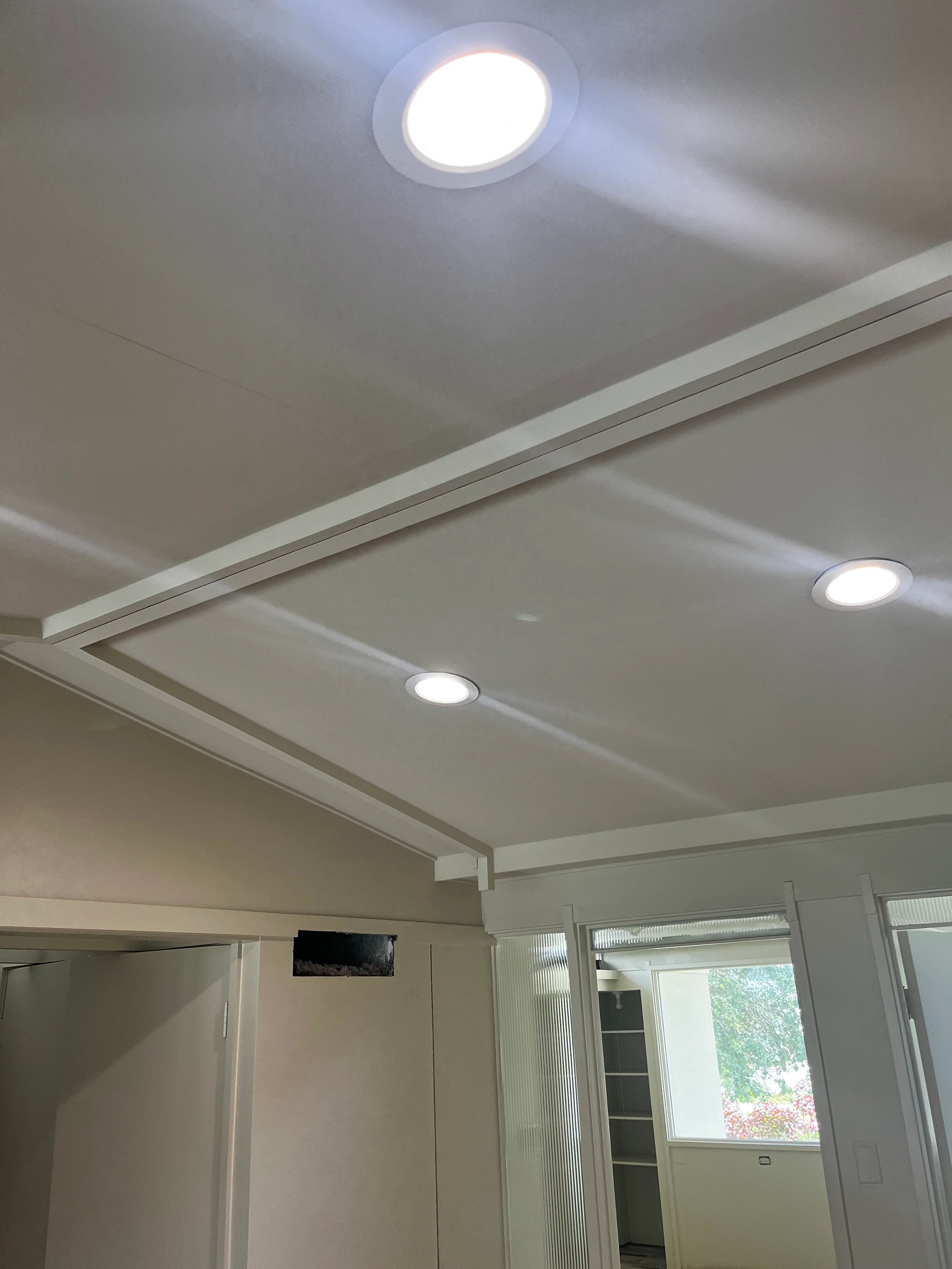 Recessed LED lighting installed in coffered drywall ceiling with white trim and glass doors