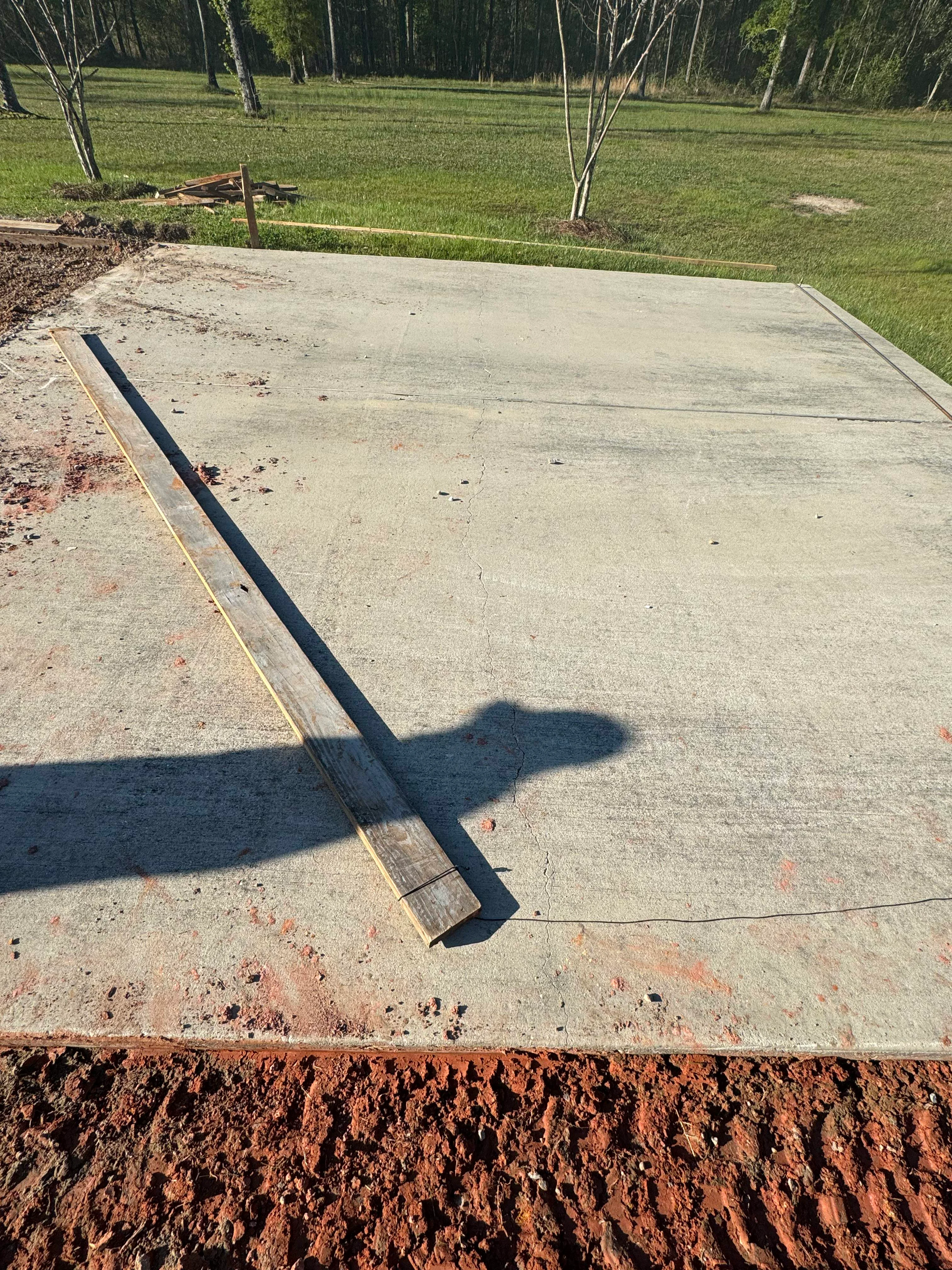 Newly poured concrete foundation slab with control joints and edge forms on prepared ground