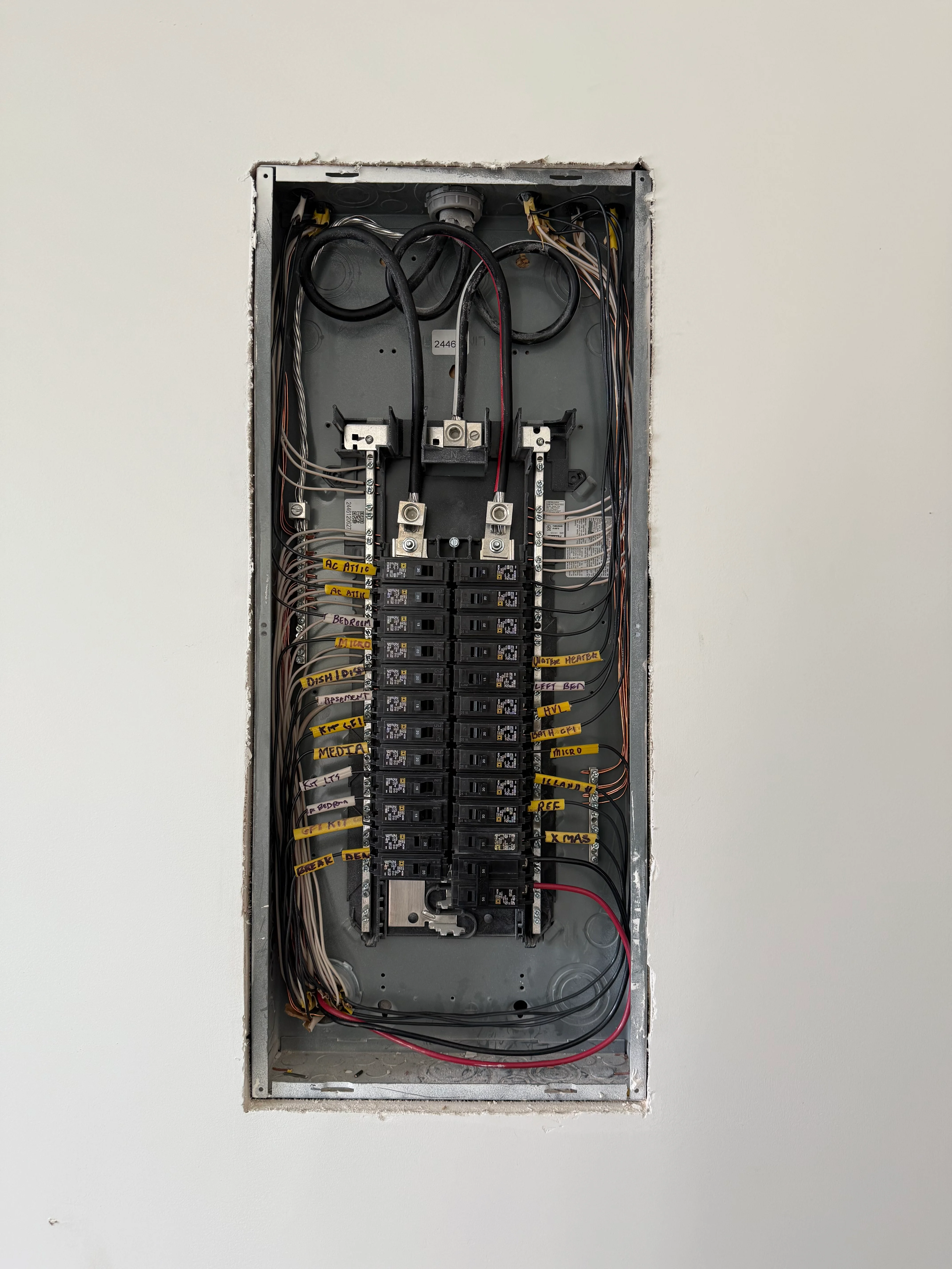 Interior view of installed electrical panel with dual breakers, organized wiring, and labeled circuits