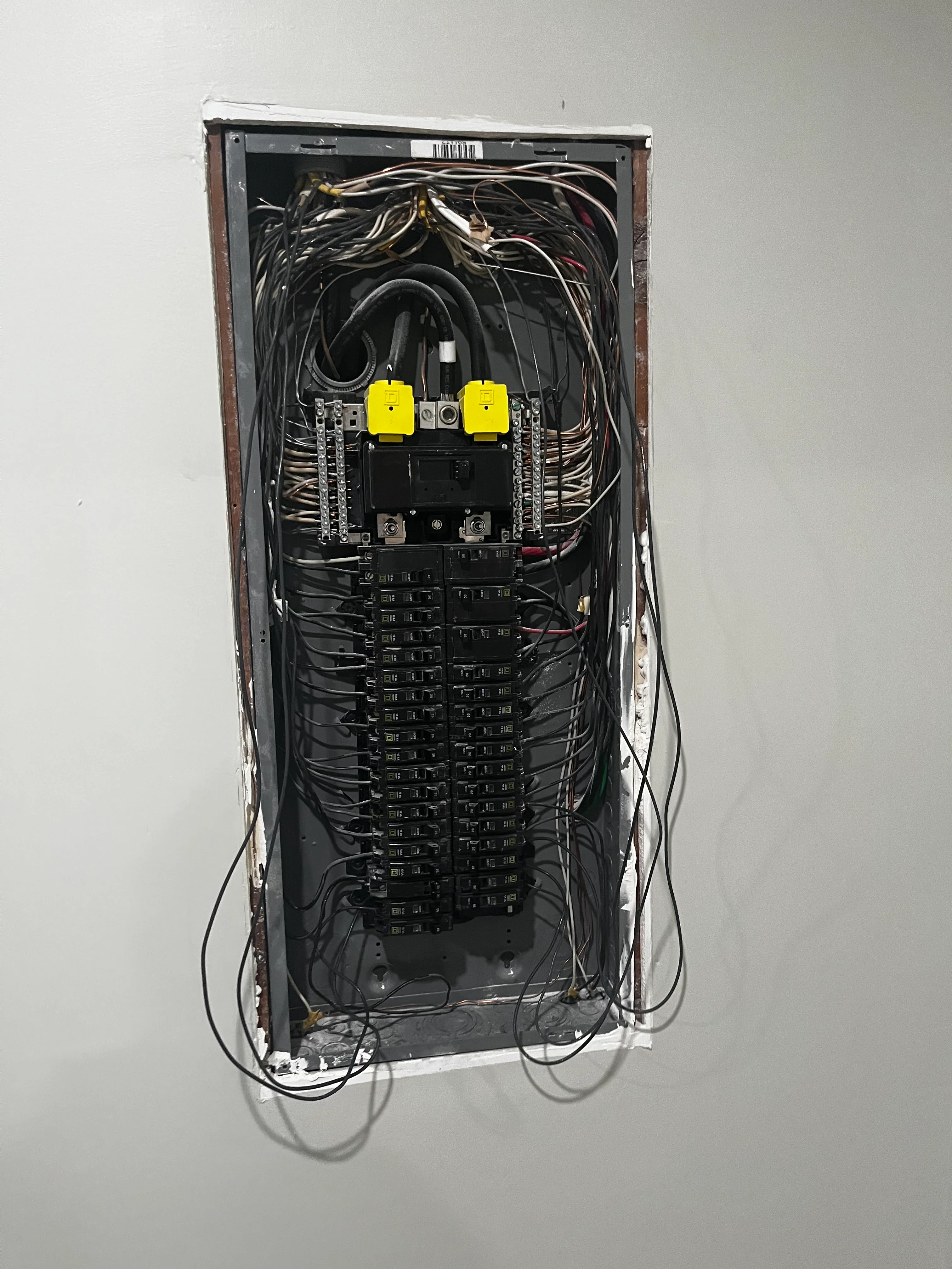 Electrical panel with dual yellow main breakers and organized circuit breaker layout with routed wiring