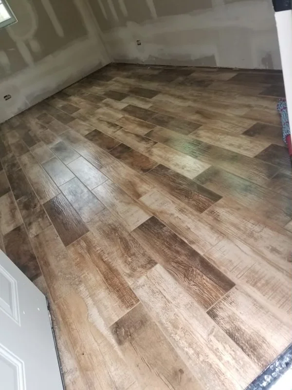 Herringbone pattern luxury vinyl plank flooring in warm wood tones installed in residential space