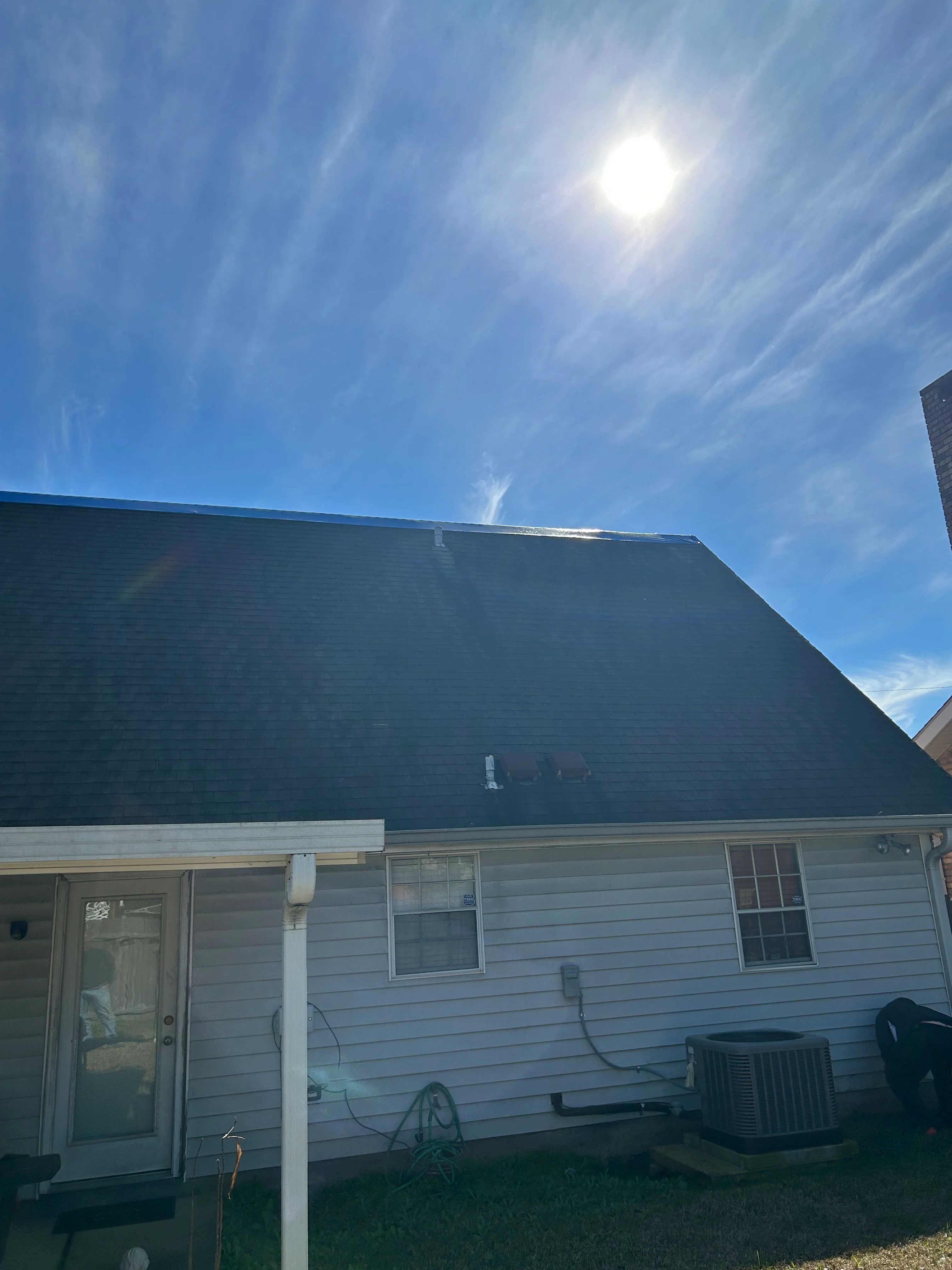 New dark asphalt shingle roof installed on residential home with white siding