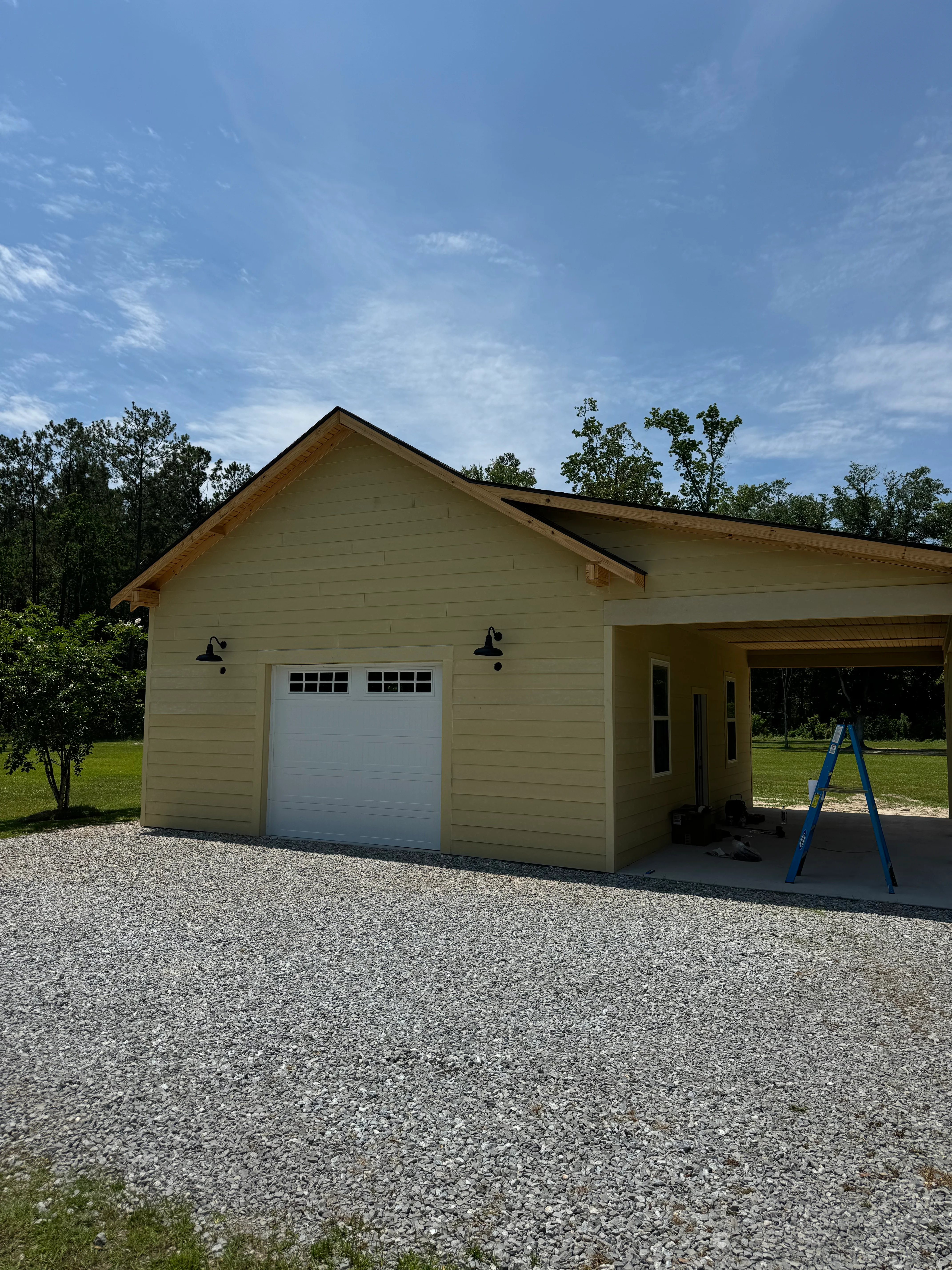 Newly constructed cream-colored garage with white door and covered porch extension