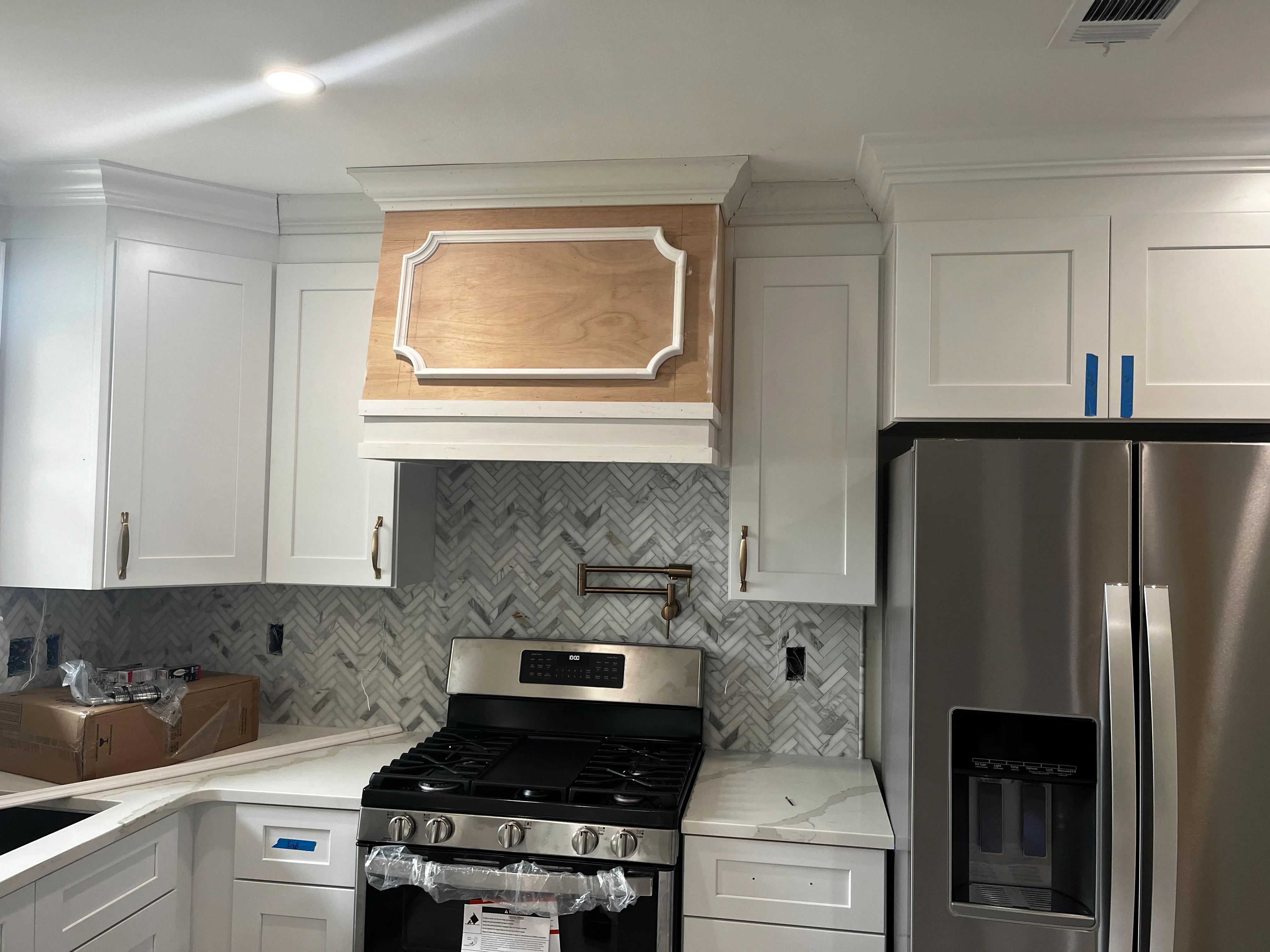 Modern kitchen with white cabinets, custom range hood, and herringbone tile backsplash