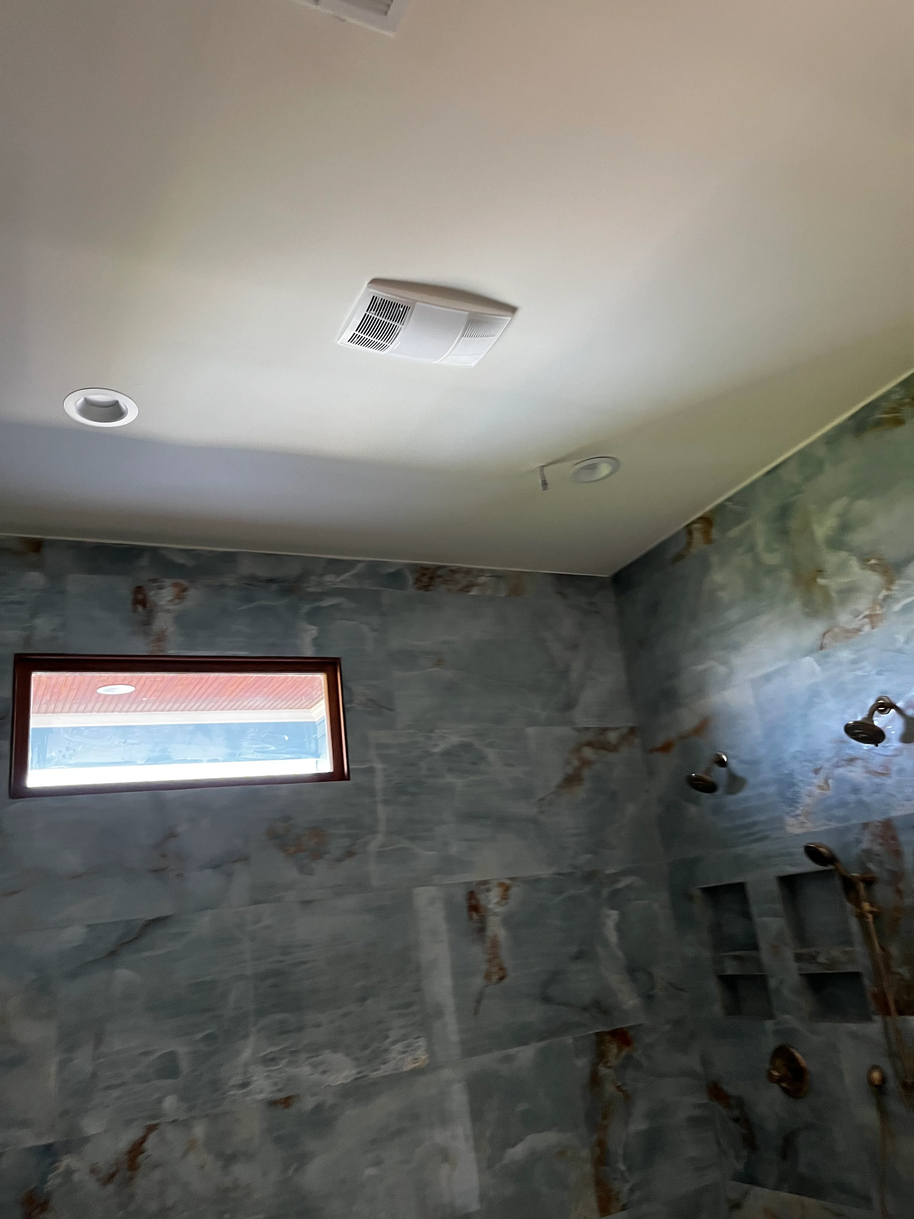 Bathroom under renovation with gray tile walls, recessed lighting, and ceiling exhaust fan