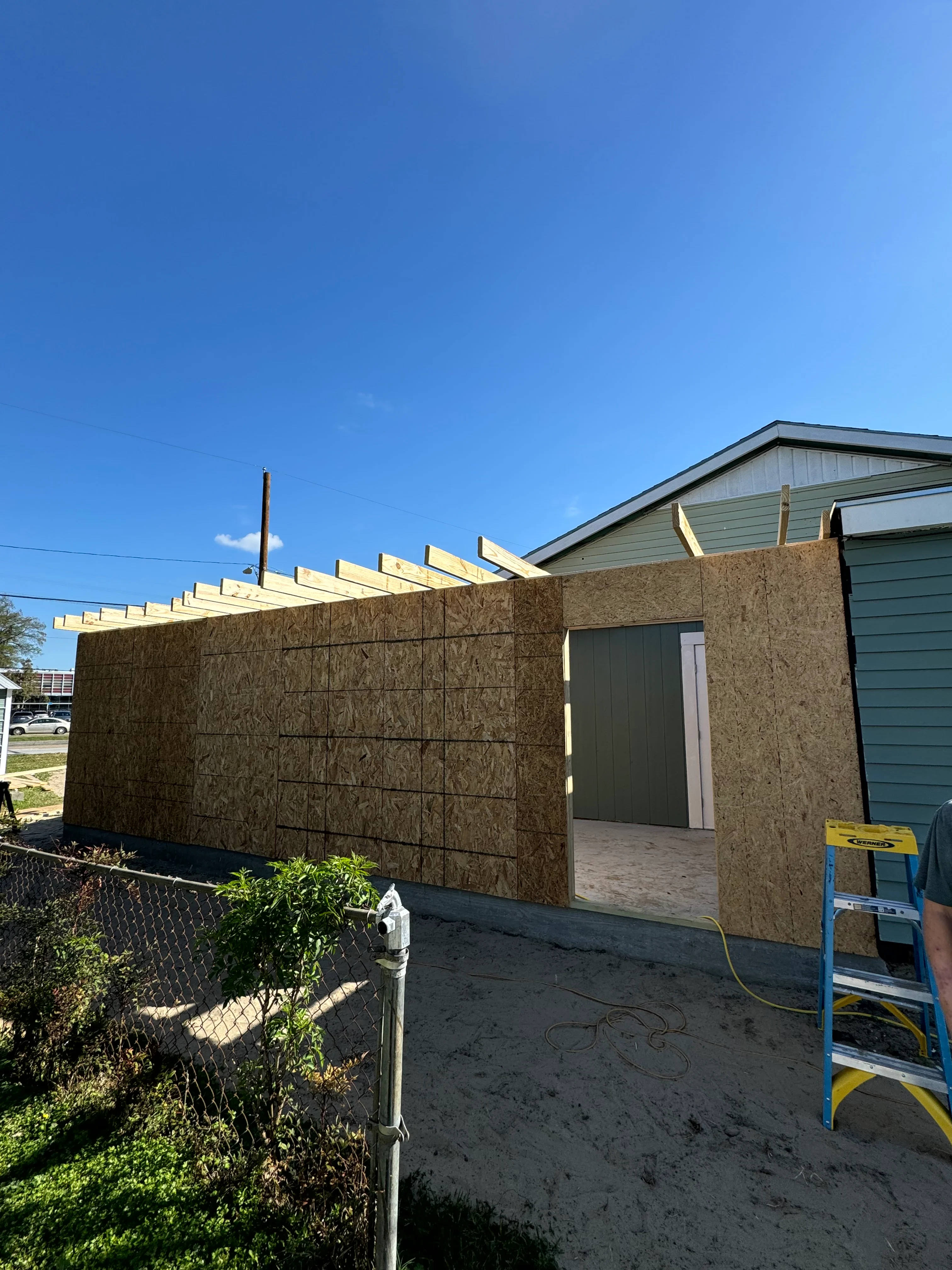 New construction addition with OSB walls and exposed roof framing in progress