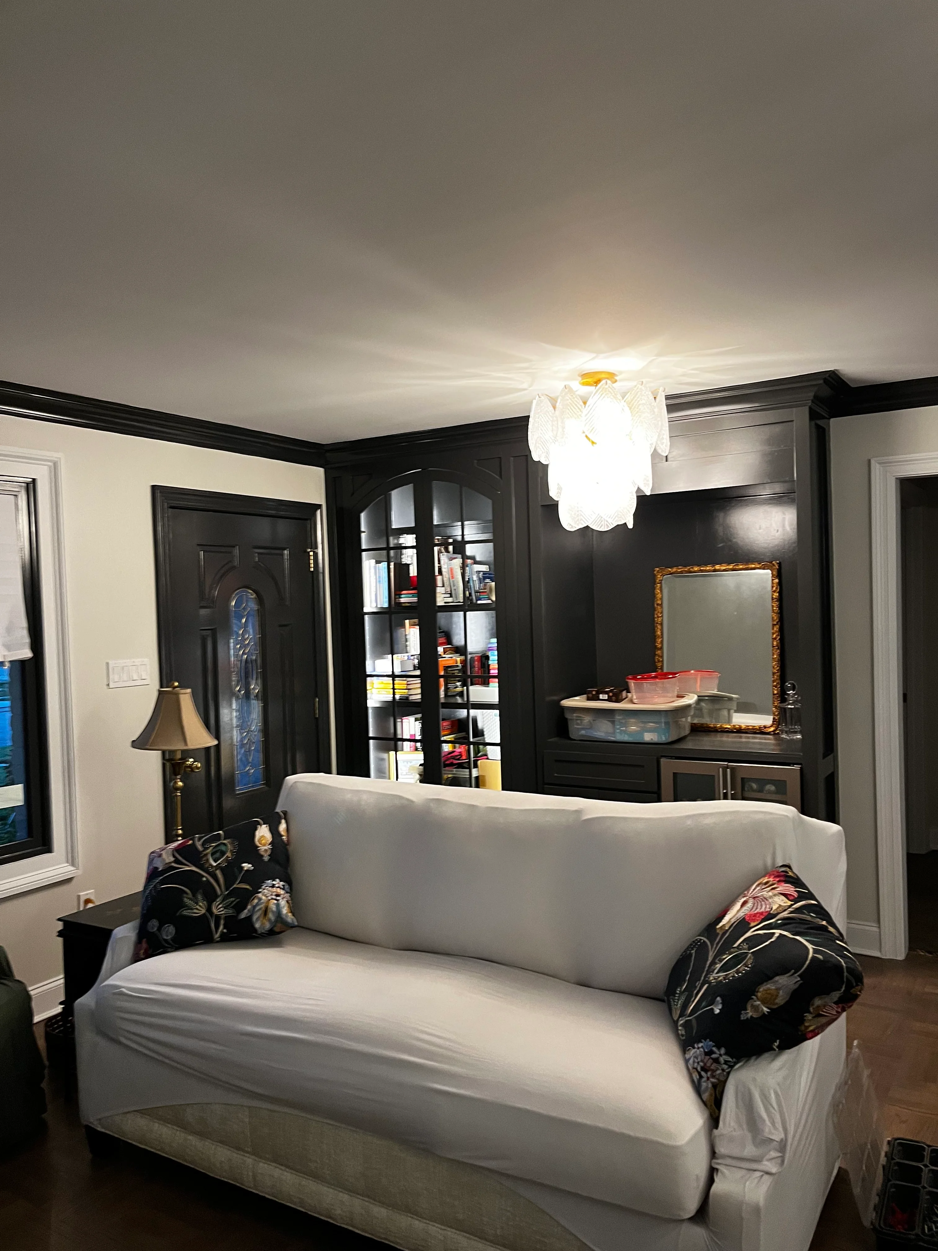 Master bedroom with white sofa, black cabinetry, crown molding, and modern pendant lighting